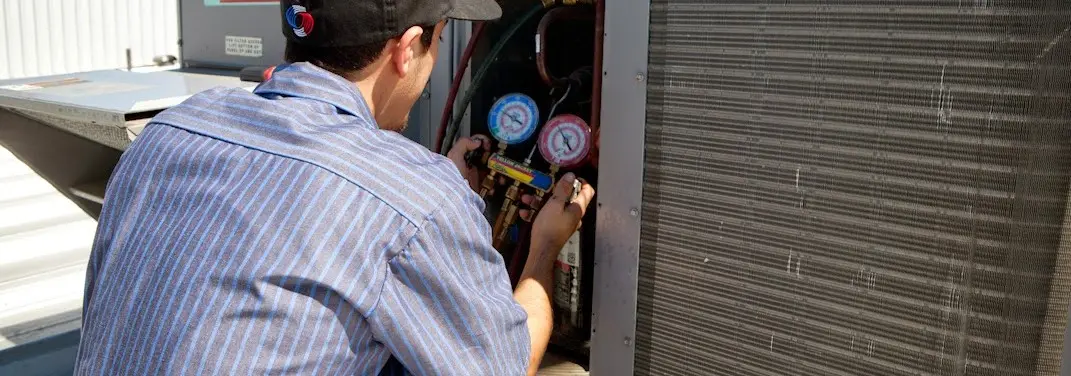 HVAC technician servicing a condenser unit in Pasco
