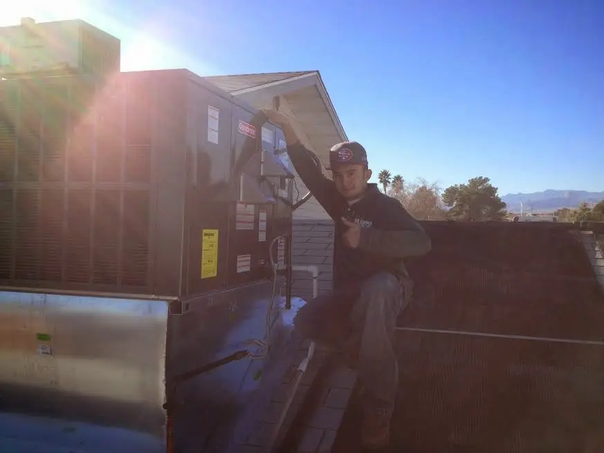 HVAC technician performing AC Tune-Up on a rooftop unit in Pasco